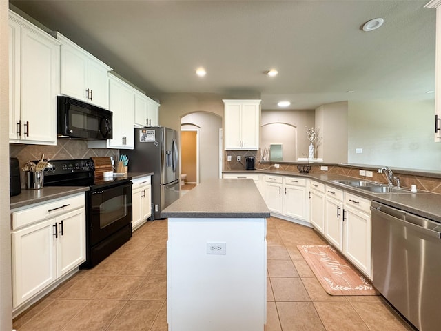 kitchen featuring tasteful backsplash, a center island, black appliances, arched walkways, and a sink