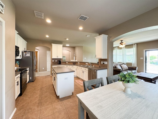 kitchen featuring ceiling fan, arched walkways, visible vents, black appliances, and a center island