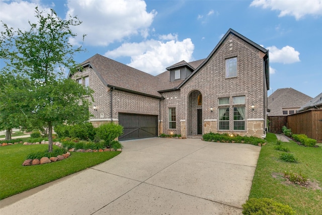 english style home with brick siding, fence, driveway, and a front yard