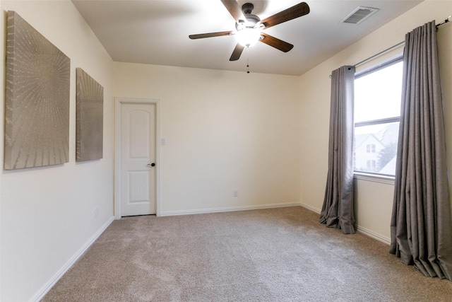 carpeted empty room with a ceiling fan, visible vents, and baseboards