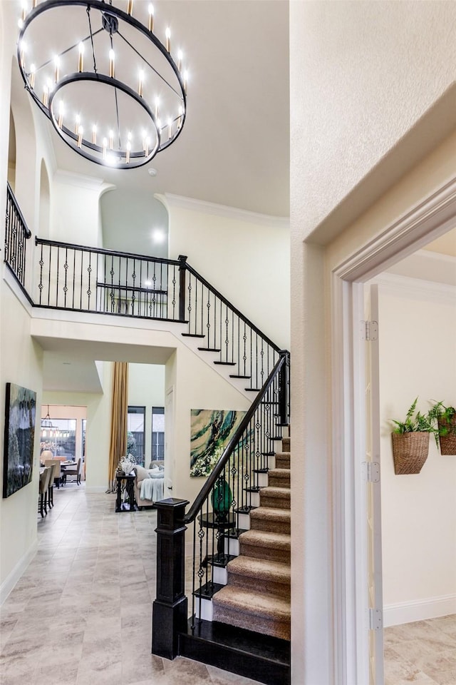 staircase with a chandelier, baseboards, ornamental molding, and a towering ceiling