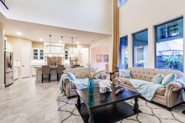 living room with an inviting chandelier, a towering ceiling, and baseboards