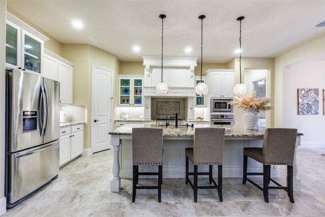 kitchen with stainless steel appliances, glass insert cabinets, tasteful backsplash, hanging light fixtures, and white cabinets
