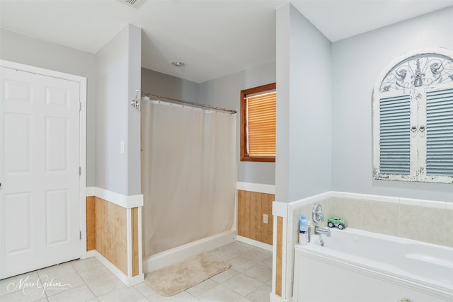 full bathroom featuring a bath, a shower with curtain, tile patterned flooring, and a wainscoted wall