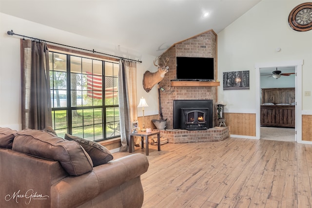 living room with lofted ceiling, a wainscoted wall, a brick fireplace, hardwood / wood-style floors, and ceiling fan