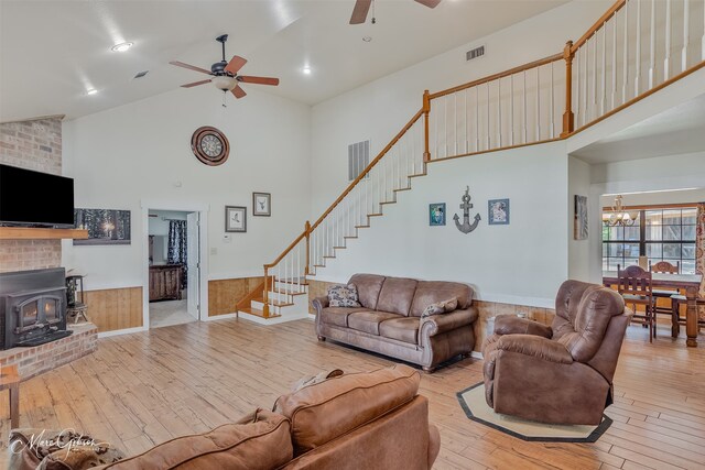 living area with a wood stove, visible vents, high vaulted ceiling, hardwood / wood-style flooring, and ceiling fan with notable chandelier