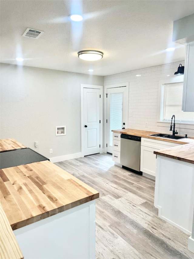 kitchen featuring stainless steel dishwasher, visible vents, a sink, butcher block countertops, and light wood finished floors