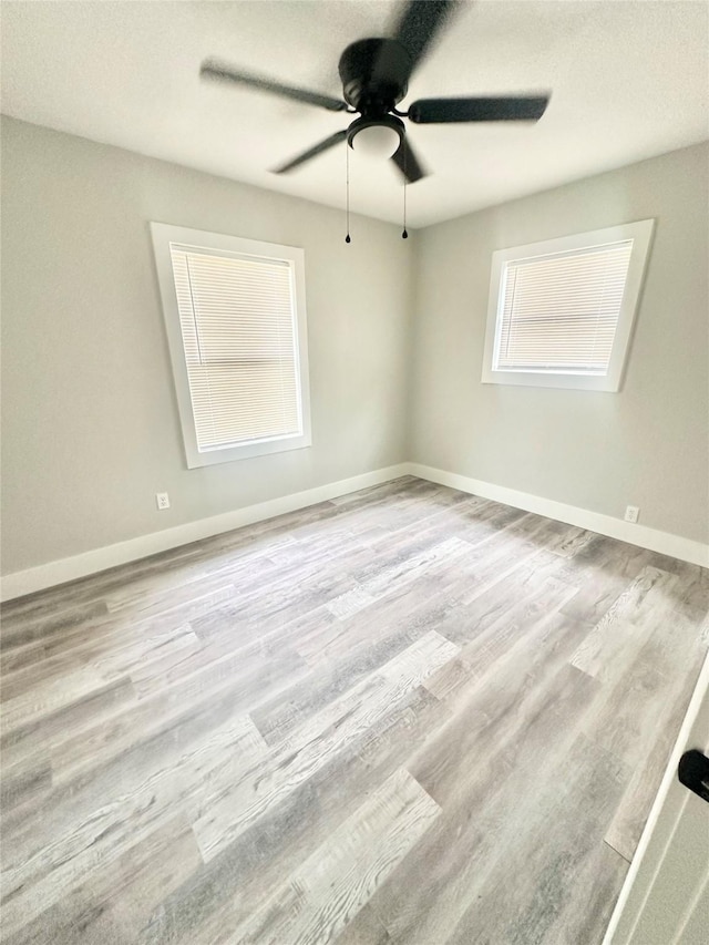 empty room featuring baseboards, a ceiling fan, and wood finished floors