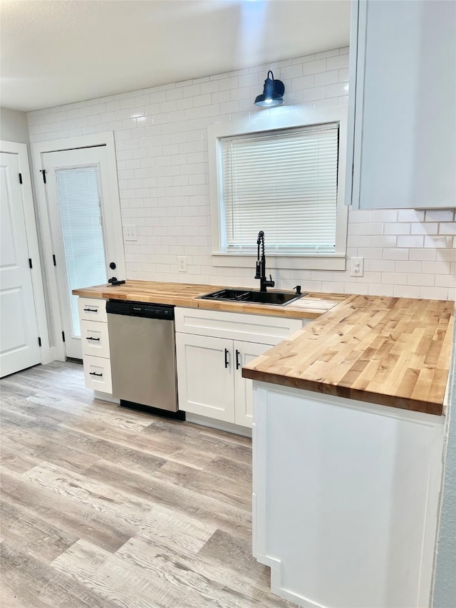 kitchen featuring tasteful backsplash, butcher block counters, stainless steel dishwasher, and a sink