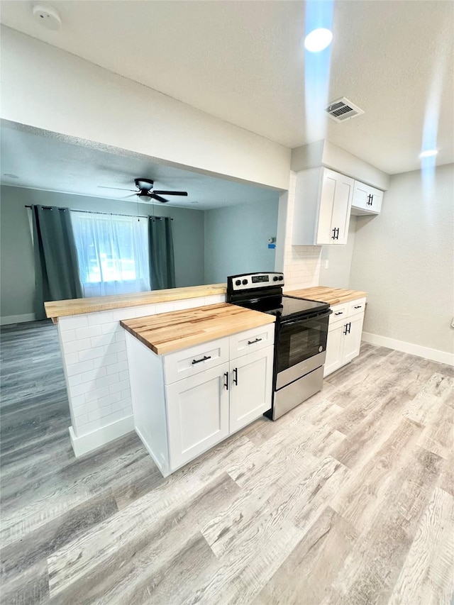 kitchen featuring visible vents, baseboards, light wood-style floors, butcher block counters, and electric range