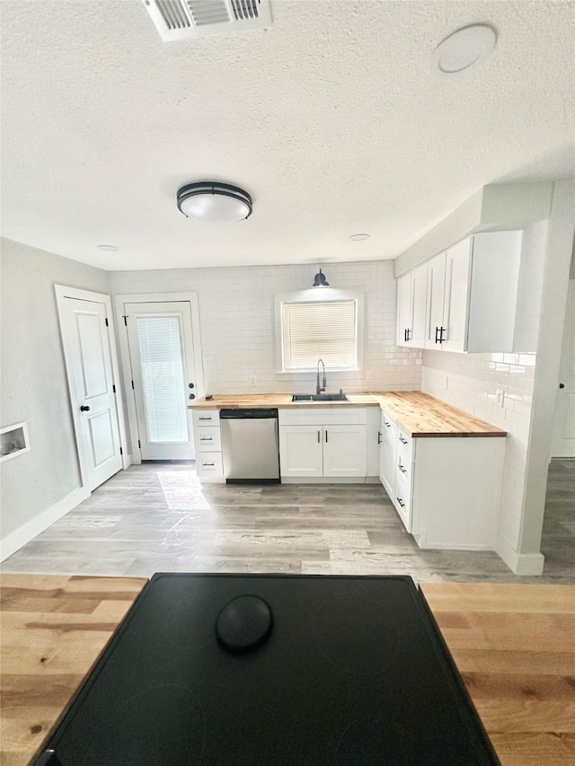 kitchen featuring wood counters, dishwasher, visible vents, and a sink