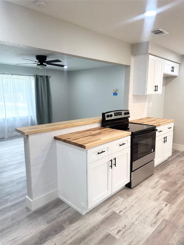 kitchen featuring a peninsula, white cabinetry, wooden counters, stainless steel range with electric cooktop, and light wood finished floors