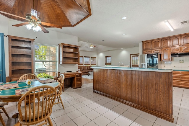 kitchen with a ceiling fan, visible vents, light countertops, refrigerator with ice dispenser, and under cabinet range hood