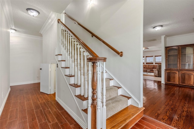 stairway featuring crown molding, a textured ceiling, and wood finished floors