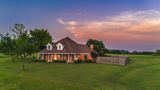 view of front of house with a front lawn, fence, a chimney, brick siding, and a porch