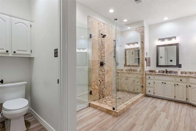 bathroom with toilet, a shower stall, wood finished floors, and vanity