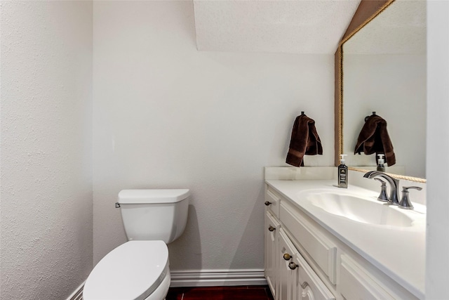 half bath with vanity, baseboards, wood finished floors, and toilet