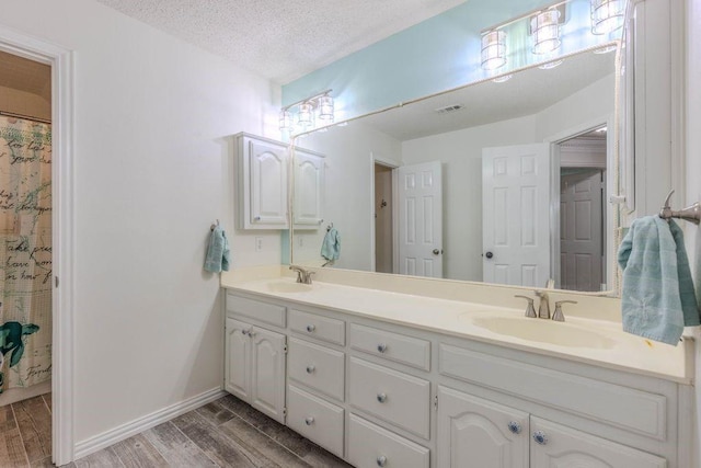 bathroom with a sink, double vanity, wood finished floors, and visible vents