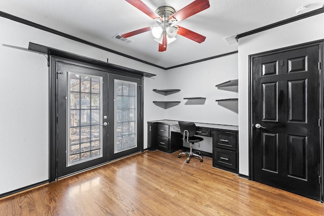 office featuring french doors, ornamental molding, a ceiling fan, built in desk, and wood finished floors