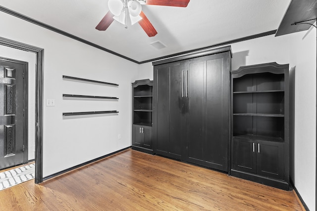unfurnished bedroom with ornamental molding, light wood-type flooring, ceiling fan, and baseboards