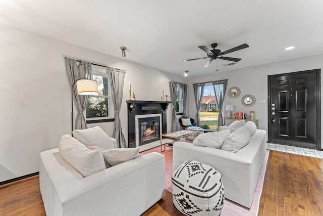 living room with a glass covered fireplace, ceiling fan, wood finished floors, and recessed lighting