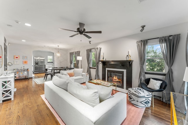 living area featuring plenty of natural light, recessed lighting, a ceiling fan, a glass covered fireplace, and wood finished floors