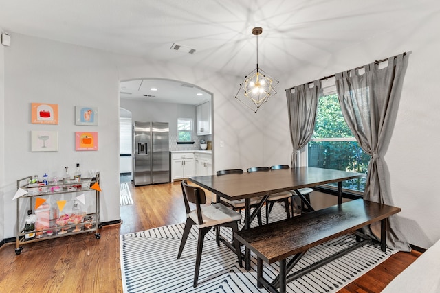 dining area featuring arched walkways, light wood-style floors, and a chandelier