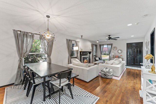 dining area with a chandelier, healthy amount of natural light, ceiling fan, and a glass covered fireplace