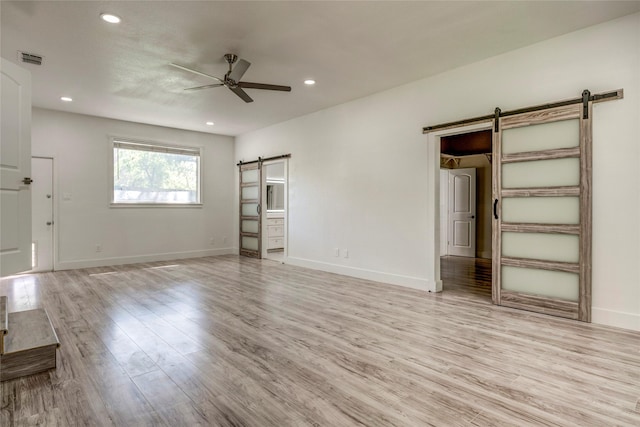 110 Pine St, Weatherford, TX 76086 - unfurnished bedroom with recessed lighting, a barn door, visible vents, and light wood-style flooring