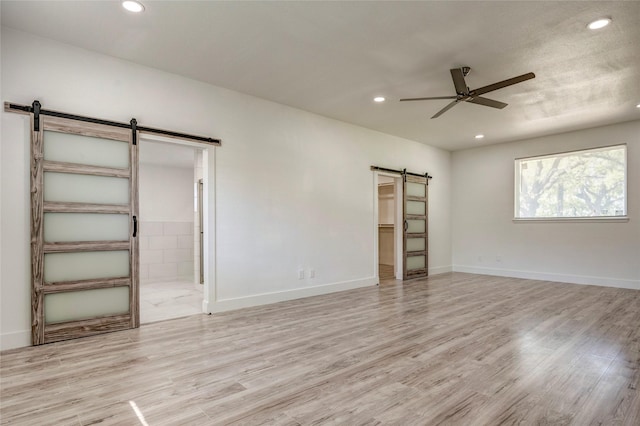 110 Pine St, Weatherford, TX 76086 - unfurnished bedroom featuring ensuite bathroom, baseboards, a barn door, light wood finished floors, and recessed lighting