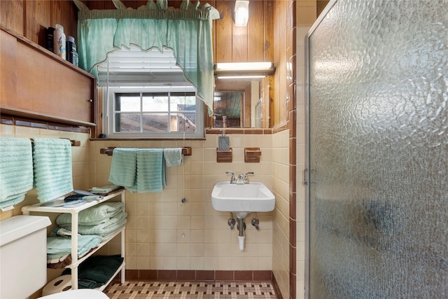 full bath featuring a shower stall, tile walls, toilet, and a sink
