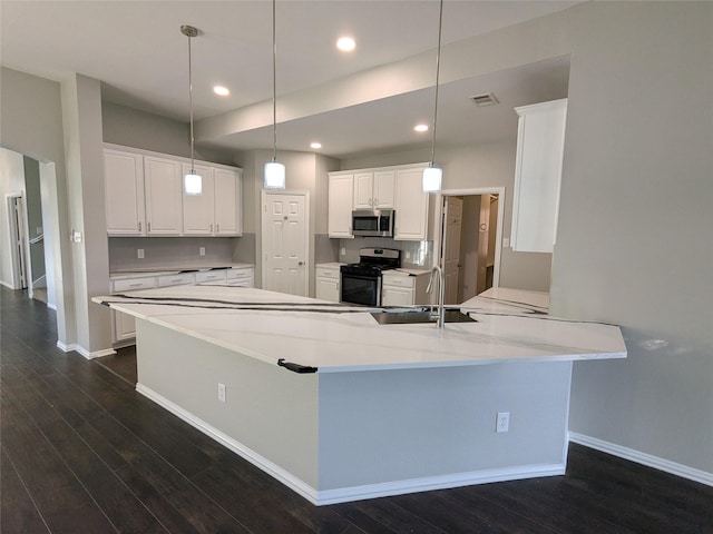 kitchen featuring a sink, a peninsula, white cabinetry, appliances with stainless steel finishes, and dark wood finished floors