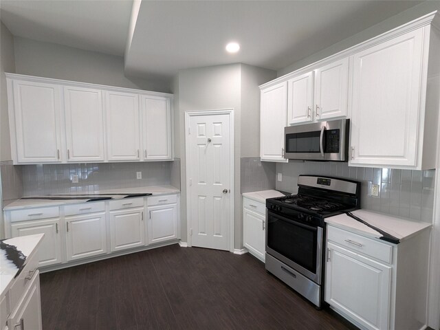 kitchen featuring white cabinets, stainless steel appliances, backsplash, and dark wood-type flooring