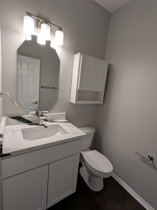 bathroom featuring wood finished floors, vanity, toilet, and baseboards