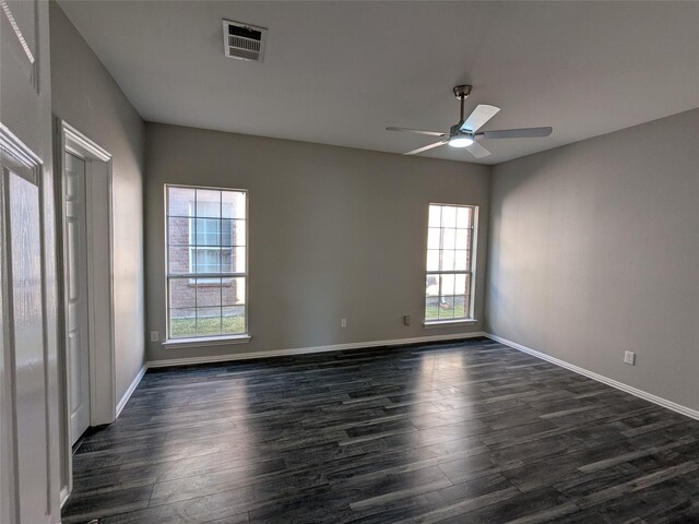 spare room with dark wood finished floors, baseboards, visible vents, and ceiling fan