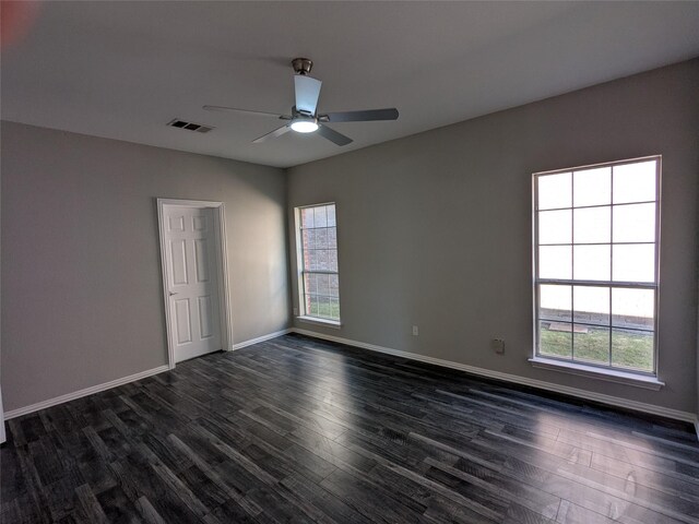 empty room with dark wood finished floors, visible vents, a ceiling fan, and plenty of natural light