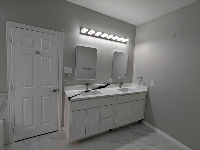 full bath featuring marble finish floor, a sink, and double vanity