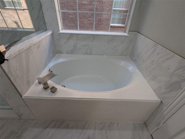 full bath featuring a garden tub and marble finish floor