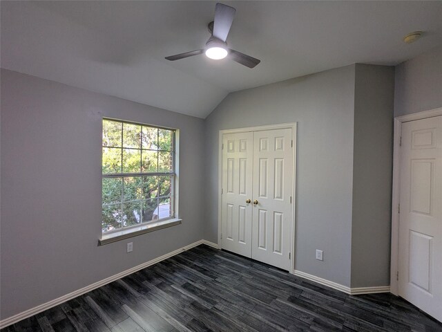 unfurnished bedroom with a closet, vaulted ceiling, ceiling fan, baseboards, and dark wood-type flooring