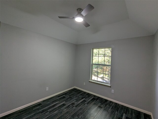 empty room with vaulted ceiling, ceiling fan, dark wood finished floors, and baseboards