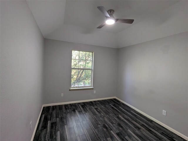 unfurnished room with dark wood-style floors, a ceiling fan, a tray ceiling, and baseboards
