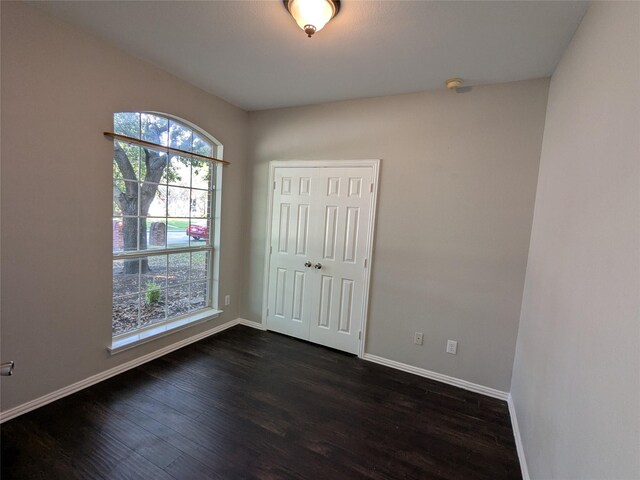 unfurnished room with dark wood finished floors, baseboards, and plenty of natural light