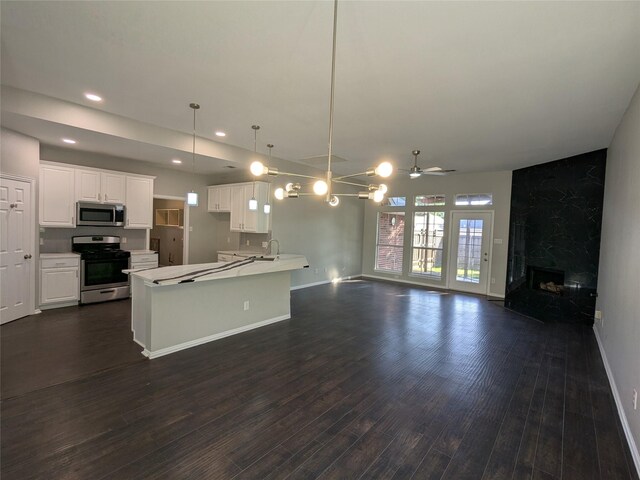 kitchen with a premium fireplace, appliances with stainless steel finishes, open floor plan, and baseboards
