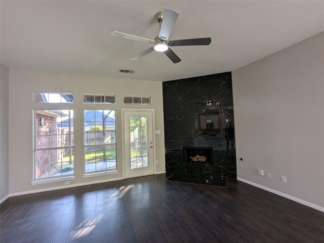 unfurnished living room with dark wood-style floors, a fireplace, ceiling fan, visible vents, and baseboards