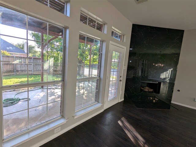 doorway featuring baseboards, wood finished floors, a premium fireplace, and plenty of natural light