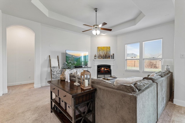 525 Northwood Dr, Oak Point, TX 75068 - living area featuring a raised ceiling, a ceiling fan, arched walkways, a warm lit fireplace, and baseboards
