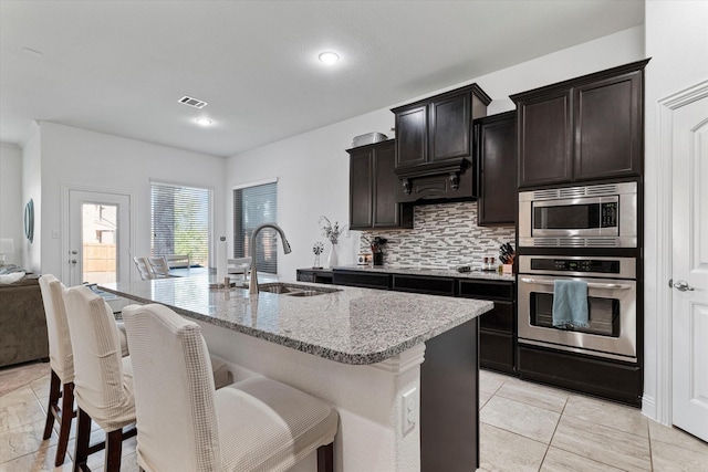 525 Northwood Dr, Oak Point, TX 75068 - kitchen with appliances with stainless steel finishes, a sink, decorative backsplash, a kitchen bar, and a center island with sink