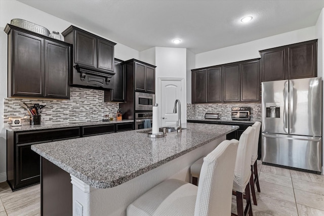 525 Northwood Dr, Oak Point, TX 75068 - kitchen with appliances with stainless steel finishes, a sink, a breakfast bar area, light stone counters, and recessed lighting