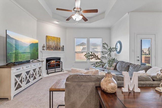 525 Northwood Dr, Oak Point, TX 75068 - carpeted living area featuring a tray ceiling, a ceiling fan, a fireplace with flush hearth, and crown molding