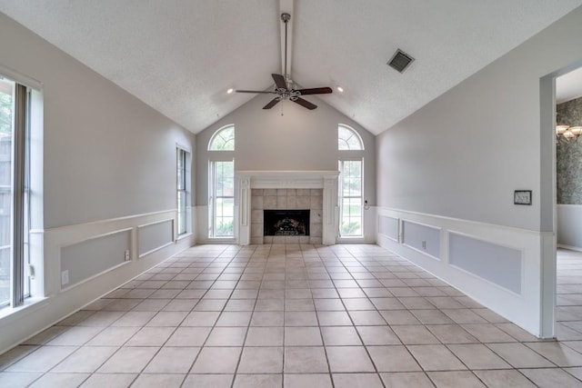 511 Windsor Way, Rockwall, TX 75087 - unfurnished living room featuring ceiling fan, a decorative wall, wainscoting, a tiled fireplace, and healthy amount of natural light